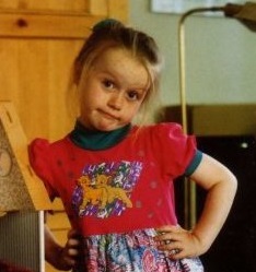Picture of a young Chloe wearing a Lion King dress looking at the camera with a "what do you want" face